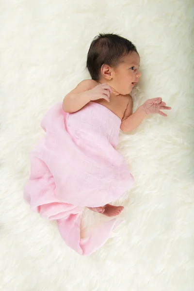 Newborn girl lying happy and relaxed on a white hair blanket — Stock Photo, Image