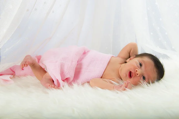 Newborn girl lying happy and relaxed on a white hair blanket — Stock Photo, Image