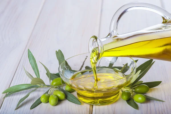 Bottle pouring virgin extra olive oil in a bowl — Stock Photo, Image