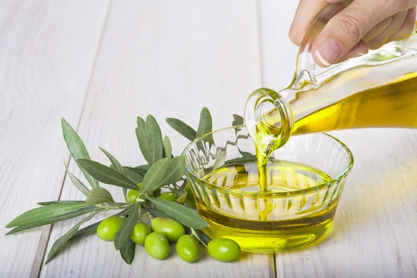 Botella vertiendo aceite de oliva extra virgen en un tazón — Foto de Stock