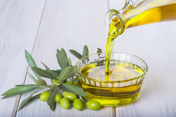 Üveg ömlött egy tál extra szűz olívaolaj — Stock Fotó