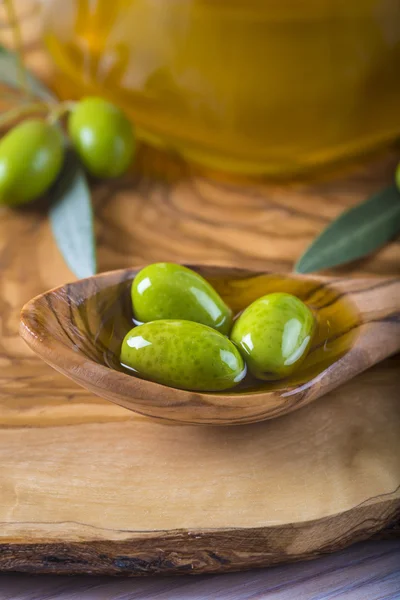 Aceitunas verdes y aceite sobre una cuchara de madera — Foto de Stock