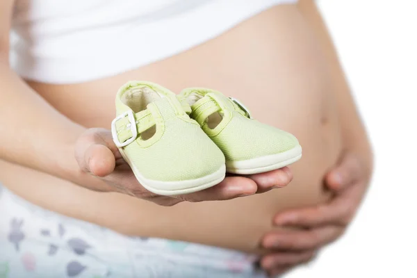 Pregnant holding baby shoes — Stock Photo, Image