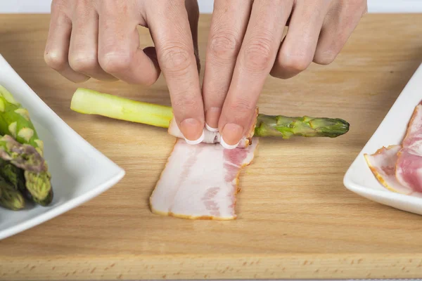 Chef che avvolge asparagi con fette di pancetta — Foto Stock