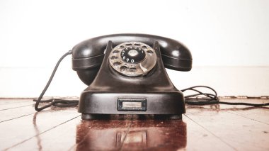 Eski ahşap bir zeminde antika siyah bir telefon.