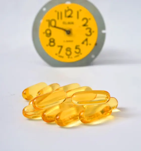 Omega 3 pills in a fron of alarm clock — Stock Photo, Image