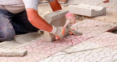 Workers tapping pavers into place with rubber mallets. Installation of granite paver blocks series with motion blur on hammers and hands. clipart