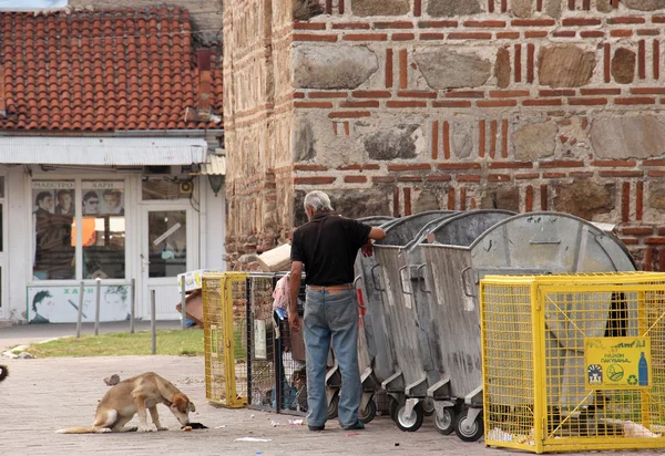 PRILEP, MACEDONIA - 13 de julio de 2016: Un buen anciano alimenta a un perro callejero con comida de un cubo de basura.Foto tomada en la ciudad de Prilep, Macedonia, el 13 de julio de 2016. — Foto de Stock