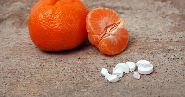 Pillole medicinali con frutta arancione su uno sfondo di cemento — Foto Stock