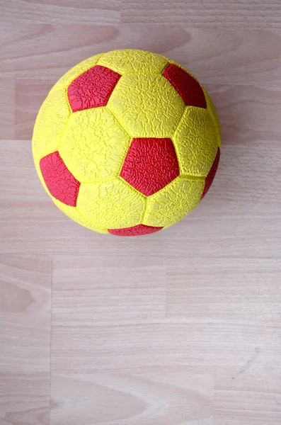 Pelota de fútbol roja y amarilla sobre una madera —  Fotos de Stock