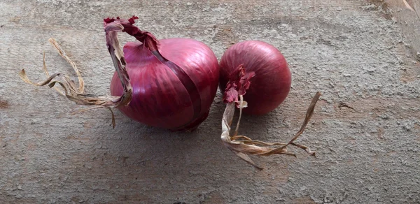 Cebollas rojas sobre fondo de madera de cemento rústico — Foto de Stock