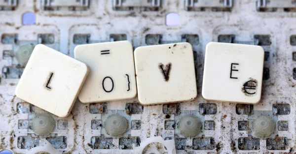 A close view of some keys on a dirty, yellowed keyboard.. text love — Stock Photo, Image