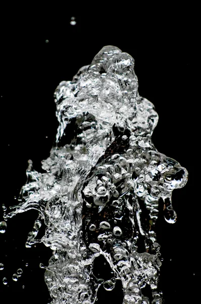 Gotas de agua levitando en el aire en la oscuridad. El agua salpicando vuela en el aire. Parte de las gotas está en foco, parte fuera del foco . —  Fotos de Stock