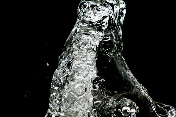 A água cai levitando no ar no escuro. Salpicos de água voam no ar. Parte das gotas está em foco, parte - fora do foco . — Fotografia de Stock