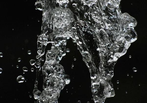 Water drops levitating in the air in dark. Splashing water fly in the air. Part of the drops is in focus, part - out of the focus. — Stock Photo, Image