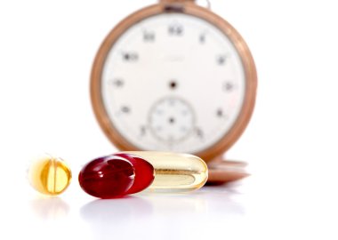 Omega 3 jel kapsül vintage cep saati önünde morina karaciğeri yağı