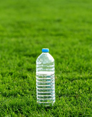 Yeşil çimenlerin üzerinde plastik su şişesi