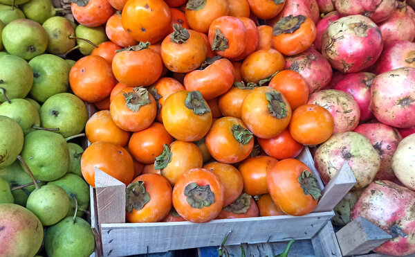Fresh ripe persimmons placed on table in market. Organic persimmon fruit in pile at local farmers market.image