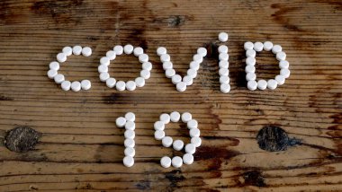 Tedavi konsepti COVID-19. Virüsün adı beyaz haplar ile yazılmış.