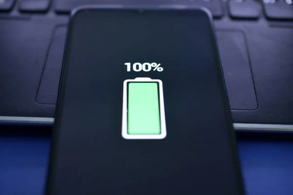 Close-up view of smartphone charging , battery level at full capacity.