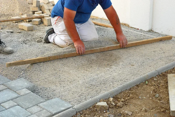건설 현장 노동자 콘크리트 벽돌 포장을 설치 하는 동안 모래를 평준화 — 스톡 사진