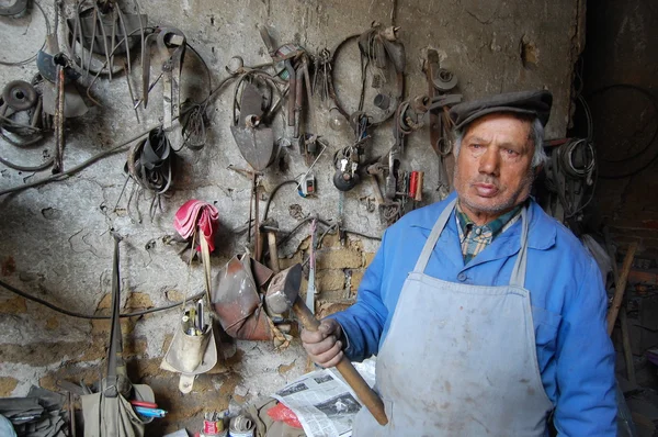 RESEN, MACEDONIA - 28 DE MAYO DE 2015: Viejo herrero con martillo en la mano posa en su taller — Foto de Stock