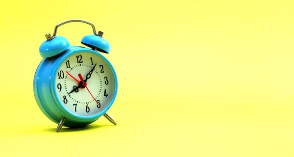 Relógio de alarme azul em um fundo amarelo — Fotografia de Stock