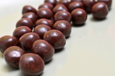 Kırmızı arka planda çikolatalı malt topları. Tüm topların parlak, yansıtıcı bir sonu var..