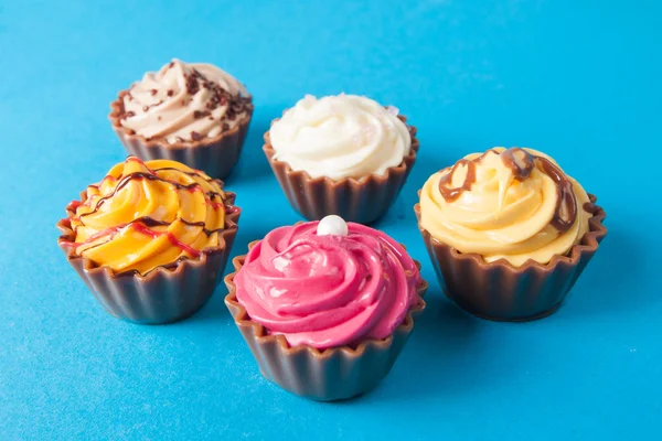 Pastelitos de cumpleaños sobre fondo azul. muchos pastelitos dulces — Foto de Stock