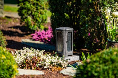 Çiçekli bir mezarda mumla birlikte mezar ışığı