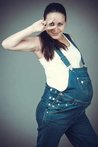 Pregnant girl in denim overalls — Stock Photo, Image