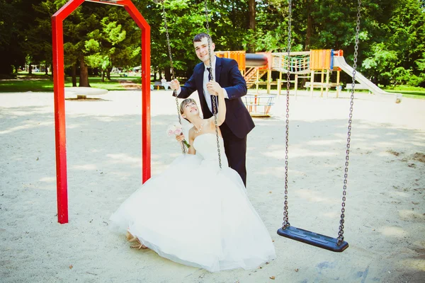 Hermosa joven pareja de boda en el parque, novia rubia en swing un — Foto de Stock