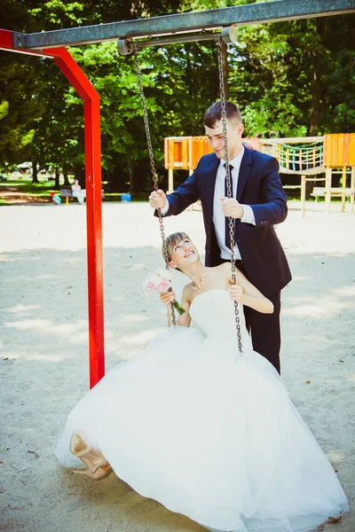 Belo jovem casal de casamento no parque, noiva loira no balanço um — Fotografia de Stock