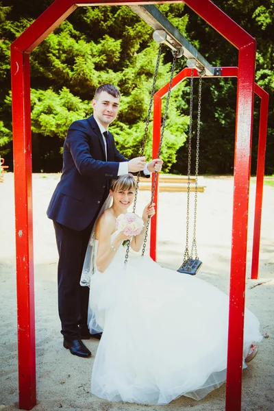 Belo jovem casal de casamento no parque, noiva loira no balanço um — Fotografia de Stock