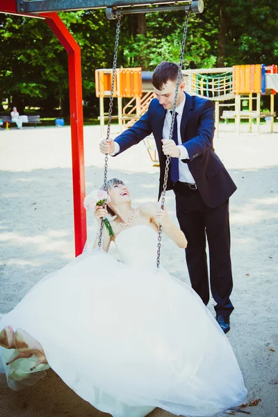 Wedding couple having fun on swing — Stock Photo, Image