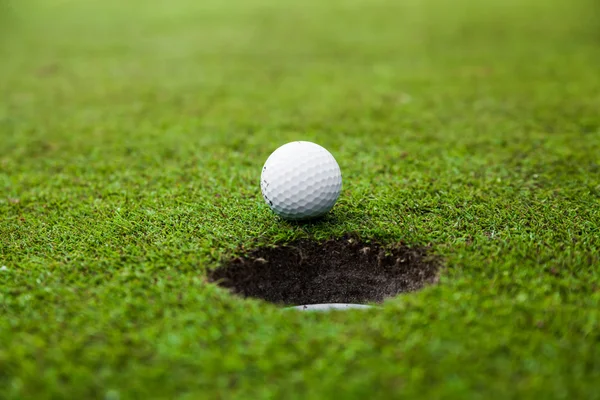 Golf ball on lip of cup — Stok fotoğraf