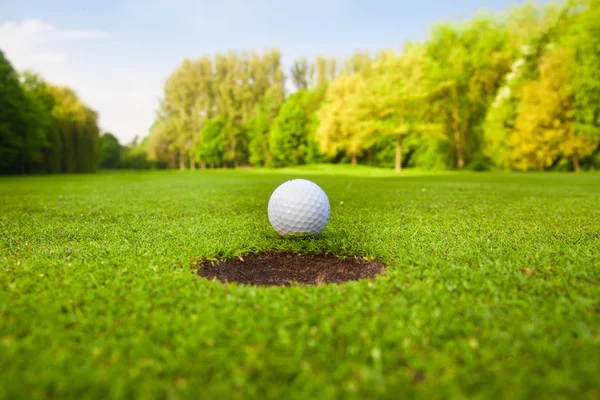 Golf ball on lip of cup — Stock Photo, Image