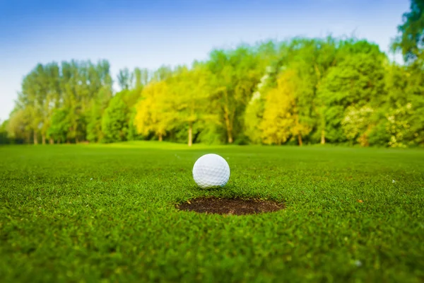 Golf ball on lip of cup — Stock Photo, Image