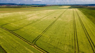 Scenic industrial landscape showing the contrast between traditional agriculture and modern energy production with wind farms and a thermal power station under a summer sky