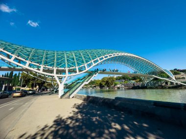 Gürcistan 'ın tarihi merkezi Tiflis' teki Kura Mtkvari Nehri 'ni kaplayan ikonik cam ve çelik Barış Köprüsü manzarası