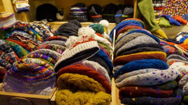 Geleneksel bir Avrupa Noel pazarında İskandinav desenli çeşitli renkli el yapımı yün taksilerin yakın çekimi. Sıcak kış aksesuarları ve mevsimlik hediyelik eşya alışverişi