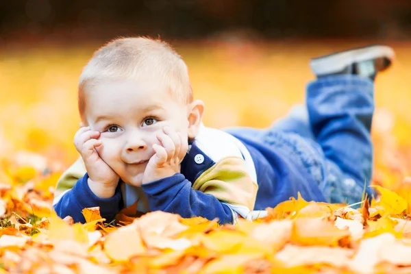 Little boy lying on the yellow leaves — Stock Photo, Image