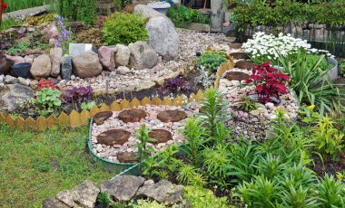 Çok katlı bir binanın yanında küçük el yapımı taşlar bahçesi. 