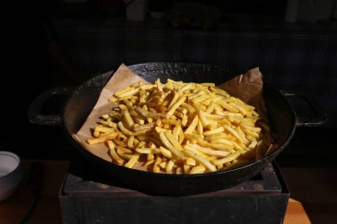 Kızarmış patates yığını siyah bir tavada yatıyor. 