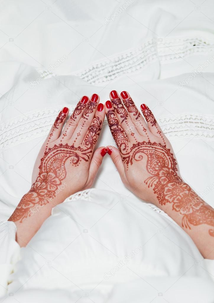 Henna tattoo on hands holding on white dress