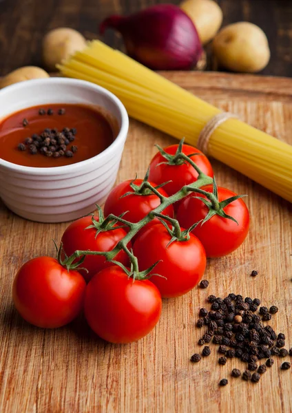 新鲜的西红柿，用原始的意大利面和胡椒厨房板上 — 图库照片