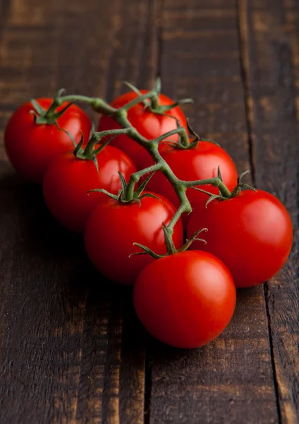 Fresh organic tomatoes on grunge wooden board — Stock Photo, Image