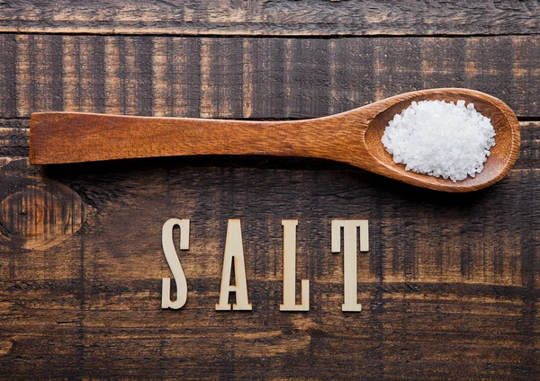 Salt on wooden spoon with letters below — Stock Photo, Image