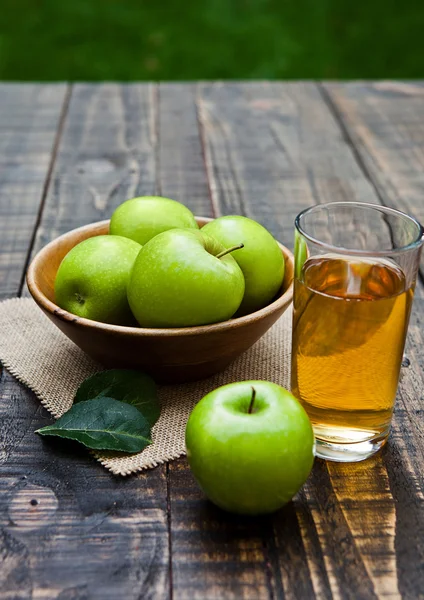 Bicchiere di succo di mela con mele verdi sane in ciotola di legno — Foto Stock