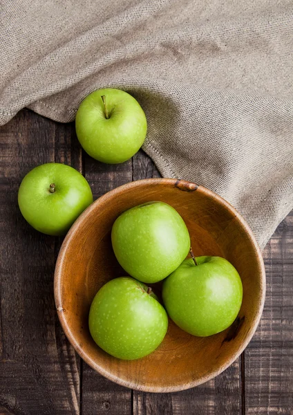 Green organic healthy apples in bowl on wooden board — Stock Photo, Image